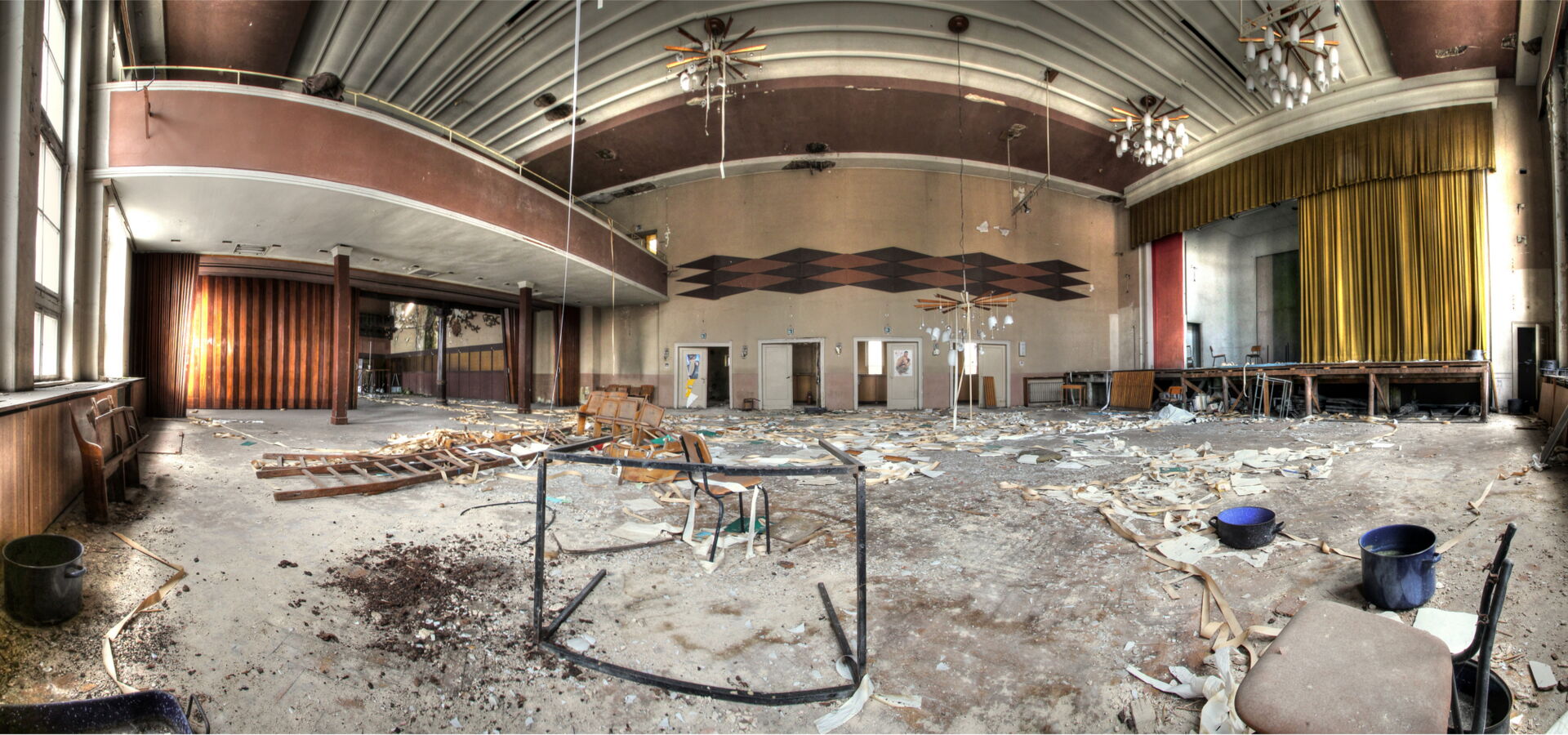 Verlassener Saal mit Bühne und Balkon.